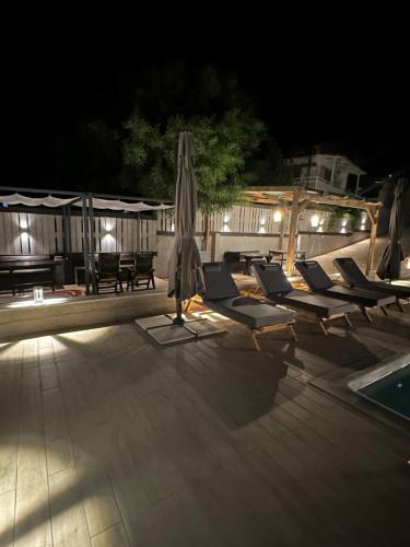 an umbrella and lounge chairs next to a pool at night at Luxury Villa Magic View 4U - katarina in Kineta
