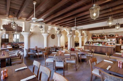 a restaurant with wooden tables and chairs and a kitchen at Al Seef Heritage Hotel Dubai, Curio Collection by Hilton in Dubai