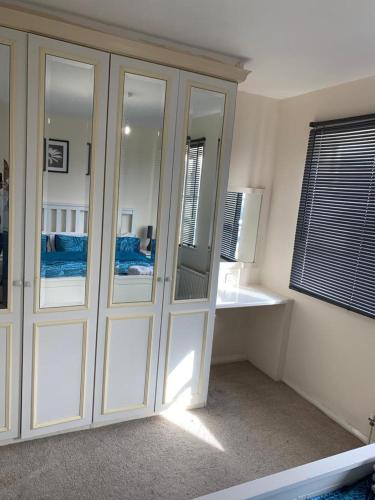 a bedroom with a large white cabinet with mirrors at Charming 2-Bed House in London in London