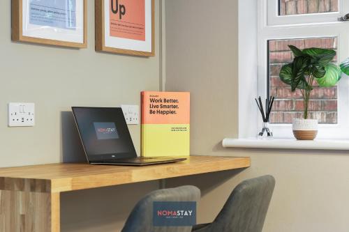 a laptop sitting on a desk with a book at NOMASTAY, Corporate, Families, Relocation, 3 bed, 2 bath, Parking, next to the hospital, university, city center in Sheffield