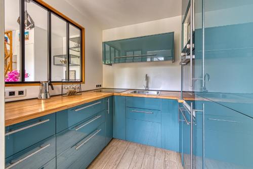 a kitchen with blue cabinets and a sink at Black Bridge - Jolie maison à Argenteuil in Argenteuil