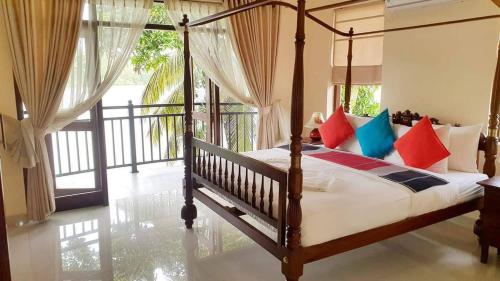 a bedroom with a canopy bed with colorful pillows at Myh Lake Front Pvt Villa with Staff, Near City, Inc Free Breakfast in Bandaragama