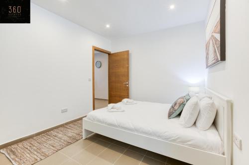 a white bedroom with a bed with white pillows at Gzira's Seashore Stayaway close to Manuel Island in Il-Gżira