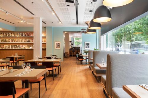 a restaurant with wooden tables and chairs and windows at Hotel Zinema7 in Donostia-San Sebastián