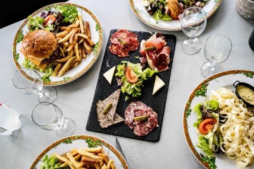 a table with plates of food and glasses of wine at Logis Hôtel La crémaillère in Hagetmau