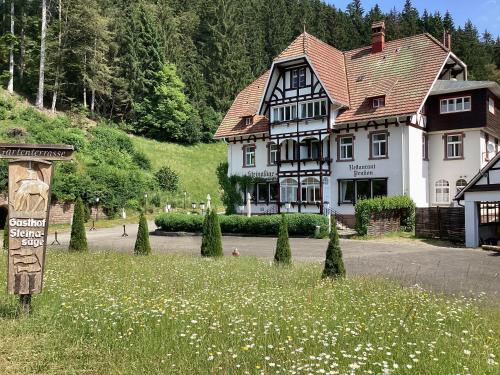 ein großes Haus mit einem Schild auf einem Blumenfeld in der Unterkunft Hotel B&B Steinasäge in Bonndorf im Schwarzwald