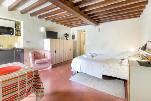 a bedroom with a large bed and a pink chair at Spacious studio apt (n.2) Ancient Palazzo in Florence
