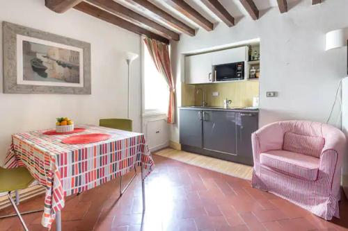 a living room with a table and a pink chair at Spacious studio apt (n.2) Ancient Palazzo in Florence