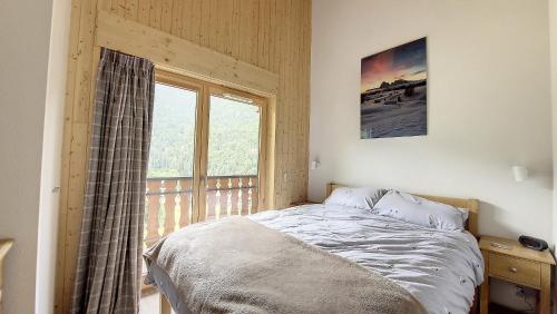 une chambre avec un lit et une grande fenêtre dans l'établissement Grand Cerf 57 58, à Saint-Jean-dʼAulps