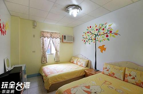 a bedroom with two beds and a tree on the wall at 綠島 梅蓮民宿 機車 潛水 浮潛 in Green Island