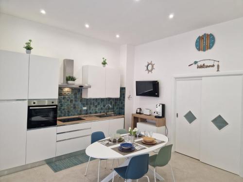 a kitchen with white cabinets and a table and chairs at ondina house in Giardini Naxos