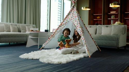 two children playing in a teepee tent in a living room at Four Seasons Hotel Kuwait at Burj Alshaya in Kuwait
