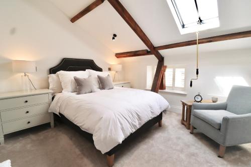 a bedroom with a large bed and a chair at Foxglove Cottage in Harrogate