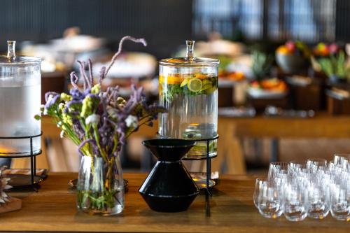 斯塔里格勒Maslina Resort的一张桌子上摆放着装水、鲜花和玻璃杯的花瓶。