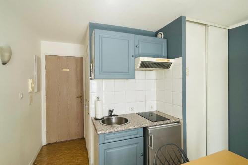 Elle comprend une petite cuisine avec des placards bleus et un évier. dans l'établissement Lovely studio near the old port and train station, à La Rochelle