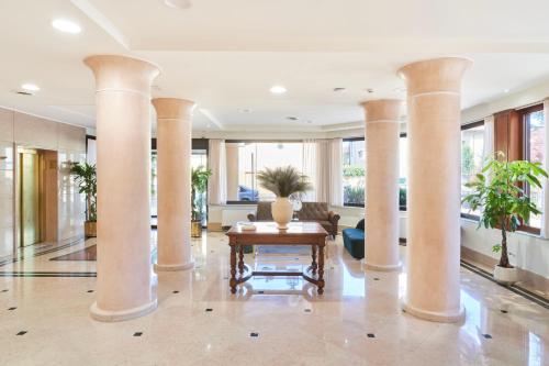 a lobby with columns and a table in the middle at Hotel Cyrano in Saronno