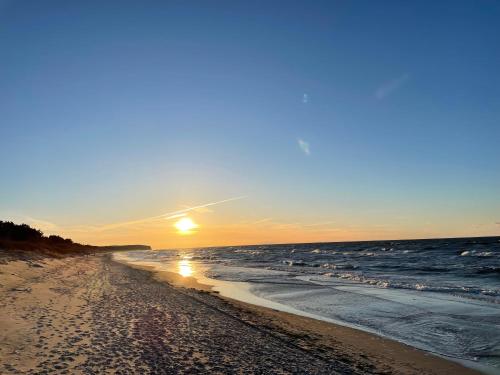 a sunset on a beach with the ocean at Plażowa Park Apartment with Garden by Noclegi Renters in Międzywodzie