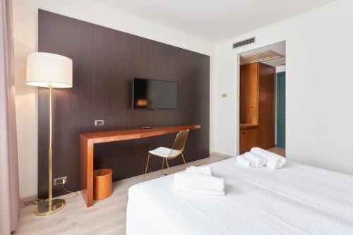 a bedroom with a bed and a desk with a television at Hotel Cyrano in Saronno