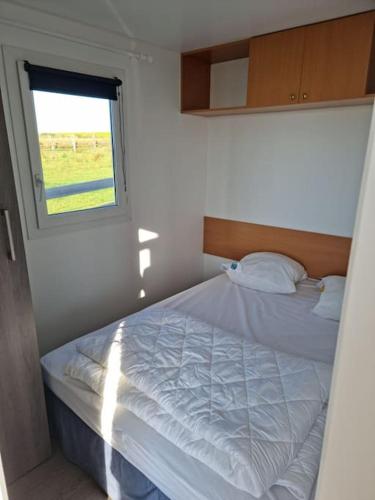 une chambre avec un lit blanc avec une fenêtre dans l'établissement Chalet Vue Mer, terrasse, nature, poney à disposition, à Dieppe