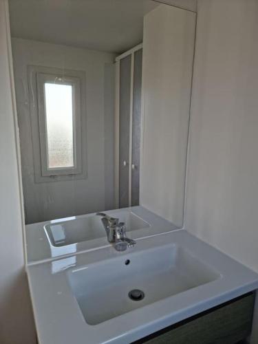 une salle de bain blanche avec un lavabo et un miroir dans l'établissement Chalet Vue Mer, terrasse, nature, poney à disposition, à Dieppe