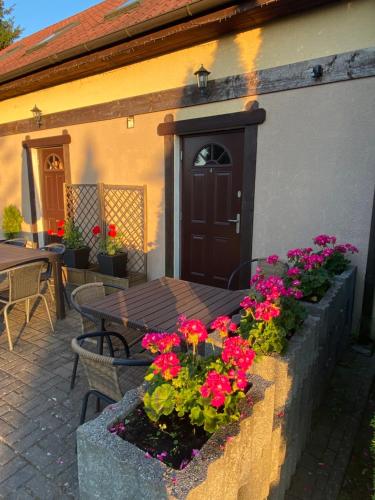 un patio con una mesa y flores frente a un edificio en Dworek Groty, en Mrągowo