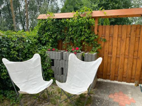 deux chaises blanches assises devant une clôture dans l'établissement Dworek Groty, à Mrągowo