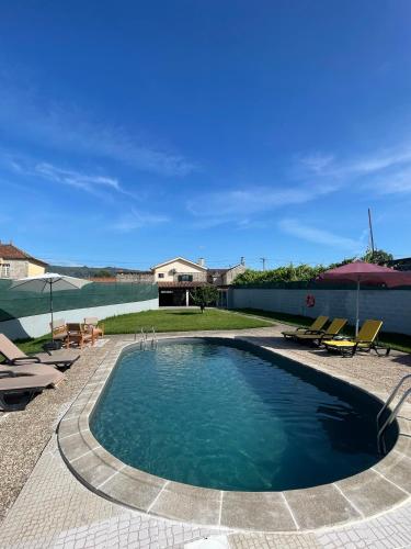 a swimming pool with chairs and a house at Refúgio da Légua in Marco de Canavezes