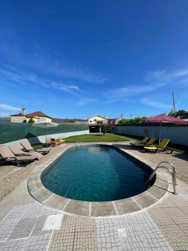 a swimming pool with chairs and a house at Refúgio da Légua in Marco de Canavezes
