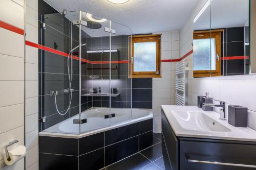 ein Bad mit einer Badewanne, einem Waschbecken und einer Dusche in der Unterkunft Chalet Bergkristall in Wengen