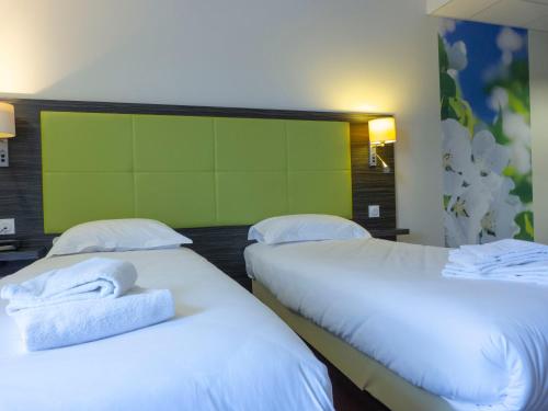 two beds in a hotel room with towels on them at Hôtel la Verriaire - The Originals in La Verrie