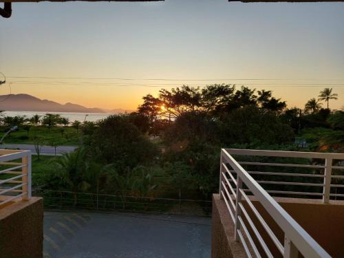 um pôr do sol a partir da varanda de uma casa em Apartamento Ubatuba Maranduba 150m da Praia em Ubatuba