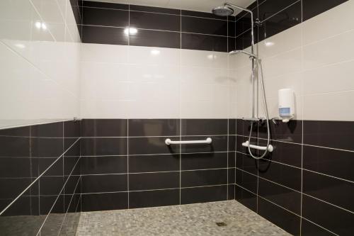 a bathroom with a shower with black and white tiles at Hôtel la Verriaire - The Originals in La Verrie