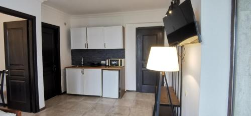 a kitchen with white cabinets and a table and a lamp at Batumi-Gonio First line Apartment in Gonio