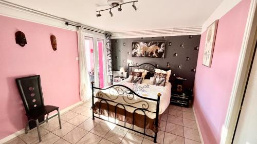 a pink bedroom with a bed and a chair at La Clef De Voute Amethyste 