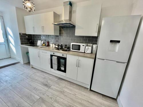 a kitchen with white cabinets and a white refrigerator at Cosy 1-Bedroom Apartment Briton Ferry, Neath Port Talbot in Briton Ferry