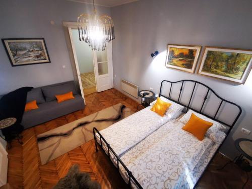 um quarto com uma cama com almofadas laranja e um sofá em Sombor 19 Central Apartment em Sombor