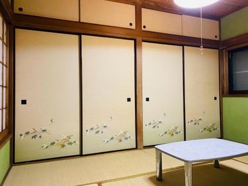 Zimmer mit vier Glasschiebetüren und einer Bank in der Unterkunft Shonan no Oka no Villa - Vacation STAY 24013v in Fujisawa