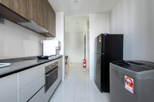 a kitchen with a black refrigerator and white cabinets at Skyring Homestay 5min to KLCC in Kuala Lumpur