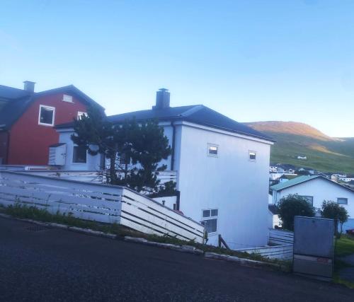 a white house with a fence in front of it at Cosy house near airport in Sørvágur