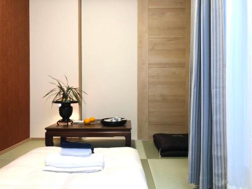 - une chambre avec un lit et une table avec des serviettes dans l'établissement Inari-Home, à Nishi-kujō-Toriiguchichō