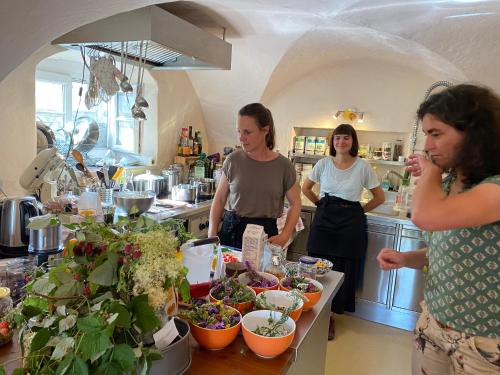 Três mulheres numa cozinha a preparar comida. em Tauglerei Doppelzimmer Bergamotte em Sankt Koloman