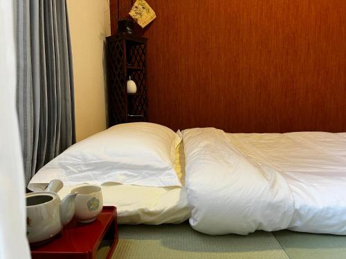 a bedroom with a bed with white sheets on it at Inari-Home in Kyoto