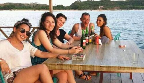 a group of people sitting at a picnic table on the water at Ekas beach floating room and restaurant in Ekas