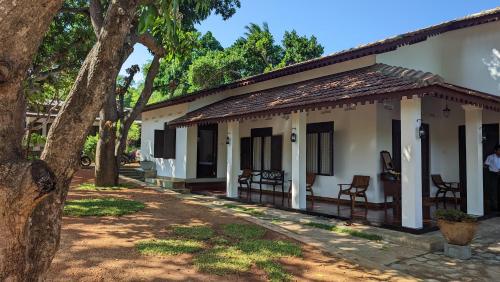 a small white house with chairs and trees at Verandas Trincomalee in Trincomalee