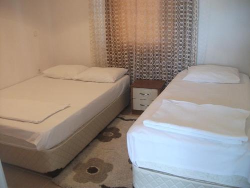 two beds in a small room with white sheets at Elite Apart Pansiyon in Gokceada Town