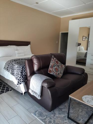 1 dormitorio con sofá de cuero y cama en Bustani 2 - Self-Catering Studio, en Edenvale