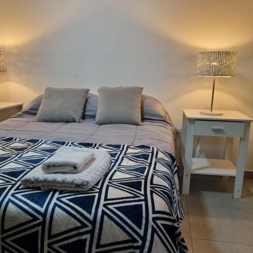 a bedroom with a bed with a table and a lamp at Happy Guest Apart 53 in Ushuaia