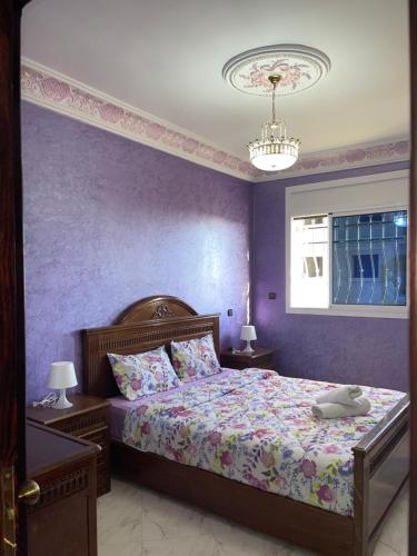 1 dormitorio con 1 cama con pared morada en Superbe maison avec terrasse à hay mohamedi, en Agadir
