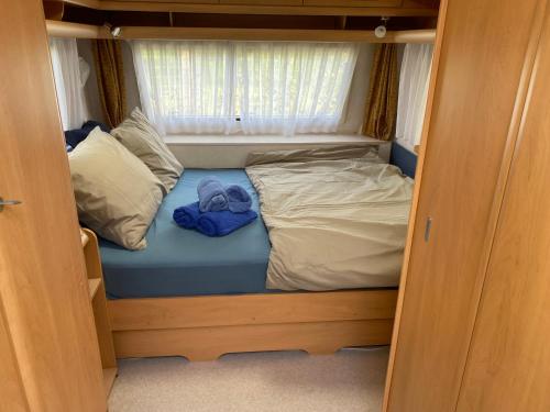 un piccolo letto in una piccola stanza con finestra di Caravan Weidezicht a Den Burg
