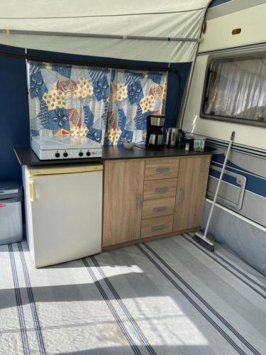 a kitchen in an rv with a table and a stove at Caravan Weidezicht in Den Burg